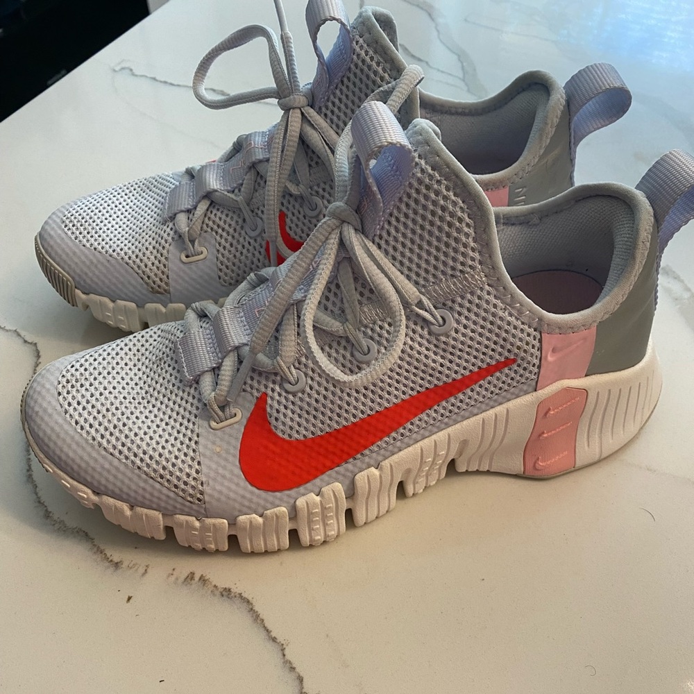 Nike metcon light blue shoe with pink and red accents.